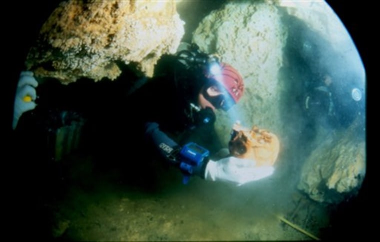 In this undated photo released on Friday, July 23, 2010, by Mexico's National Institute of Anthropology and History, a diver holds a skull belonging to a woman, known as La Mujer de las Palmas, who lived between 10,000 and 12,000 years ago, in Tulum, Mexico. Experts reconstructed what the woman may have looked like based on the remains found in a sinkhole cave near the Caribbean resort of Tulum, Mexico. Anthropologist Alejandro Terrazas says the reconstruction resembles people from southeastern Asia areas like Indonesia, even though experts had long believed the first people to migrate to the Americas where from northeast Asia. (AP Photo/ Mexico's National Institute of Anthropology and History)